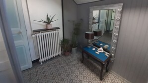 Un baño con un radiador blanco, un tocador azul, un espejo y una planta en maceta.