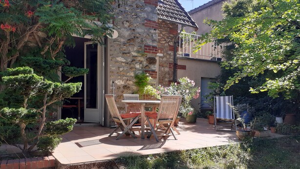 Un edificio de piedra con patio, mesas al aire libre y macetas con plantas.