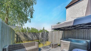 A backyard with a hot tub, wicker furniture, and a covered patio area. - 3 Ladyknowe - UK39969 (Moffat)