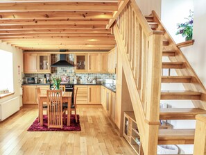Une cuisine moderne avec des meubles en bois, un coin repas comprenant une table et des chaises, et un escalier en bois.