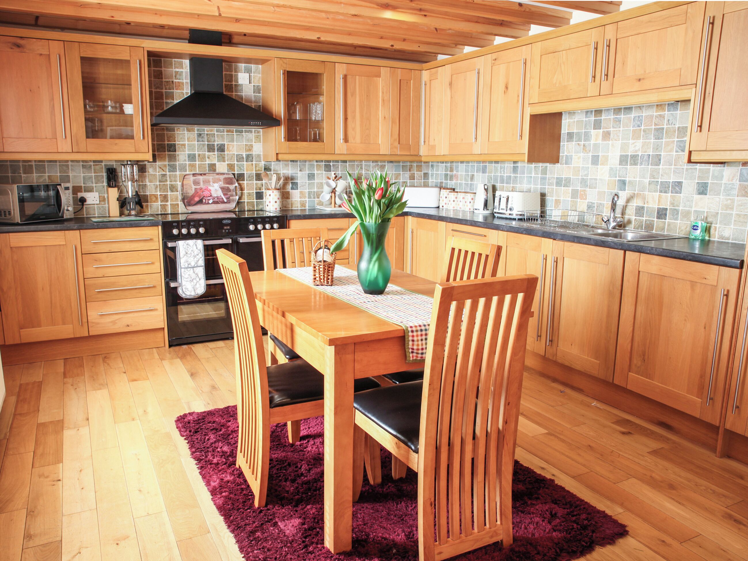 A kitchen with wooden cabinets, a stove, and a dining table with chairs.