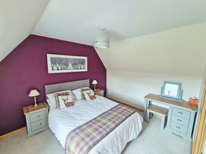 Ein Schlafzimmer mit Bett, Nachttischen, einem Schreibtisch und einem gerahmten Bild an der Wand.