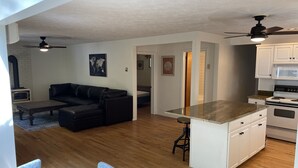 Ein moderner, offener Wohn- und Küchenbereich mit Sofa, Esstisch und Küchengeräten.
