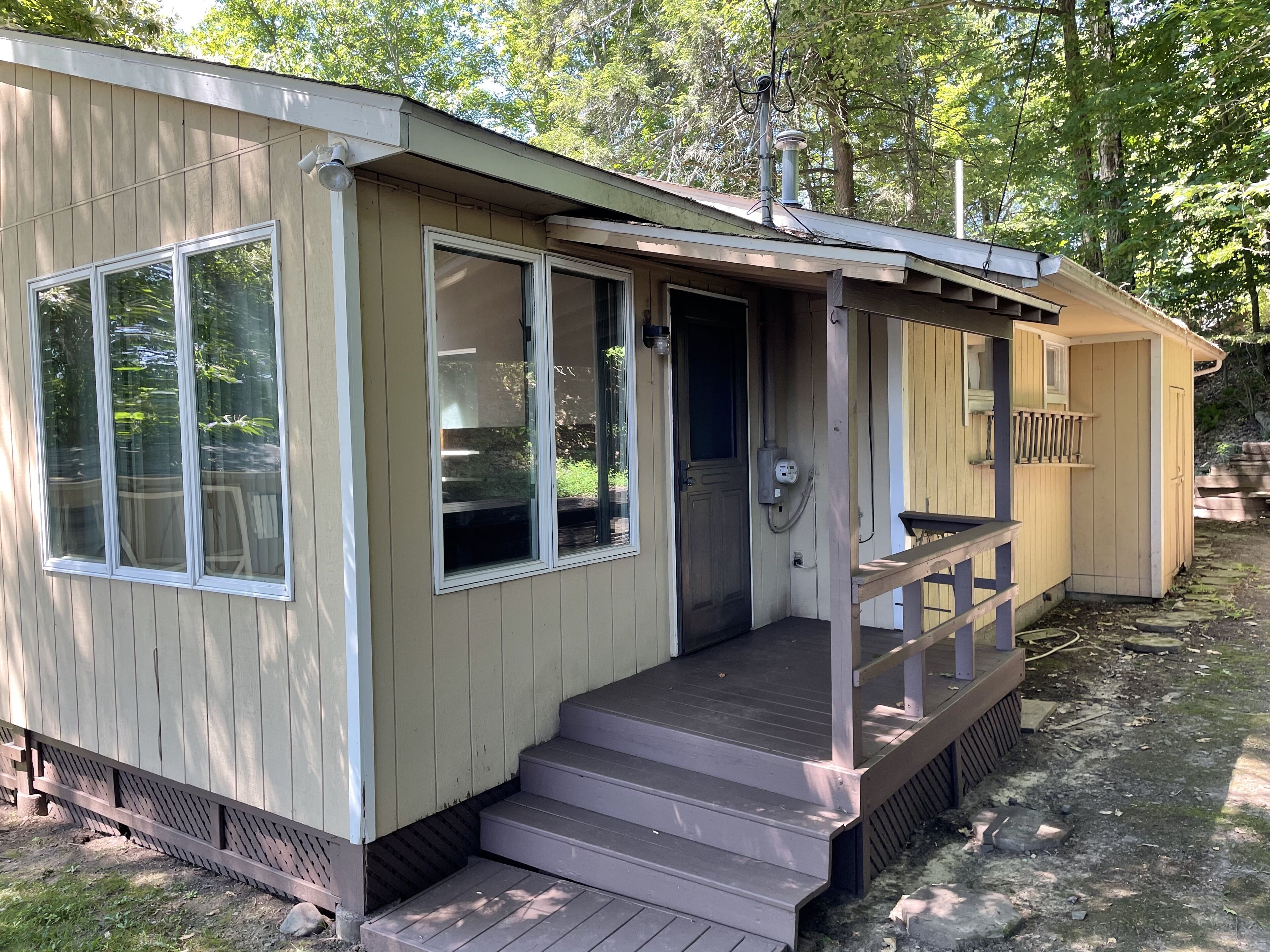 A small, single-story cabin with a front porch, a door, and a window.