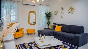 Un salon moderne avec un canapé gris, un fauteuil jaune et une table basse blanche.