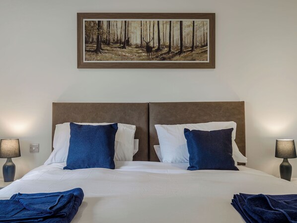 A hotel room with a large bed, two nightstands, and a framed painting above the bed. - Bramley Lodge - UK38384 (Lyonshall, near Kington)