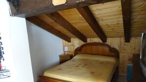 A wooden bed with a headboard, a bedside table with a lamp, and a television on a wooden stand.