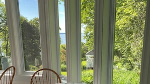 Comedor con una mesa para dos, mantel con estampado floral y vista a un jardín exuberante y un pabellón.