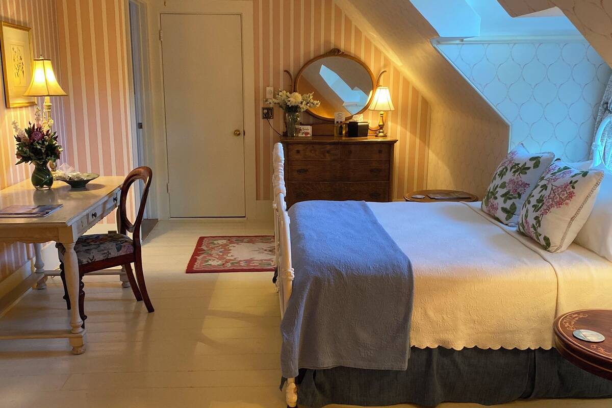 Un dormitorio con una cama, un aparador, un escritorio y una silla.