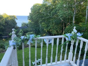 A white balustrade with a view of a grassy area and trees. - Victorian By The Sea (Lincolnville)