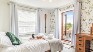 A bedroom with a bed, bedside table, and a view of the outdoors. - 3 bedroom accommodation in Beccles (Beccles)