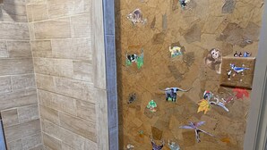 A shower area with tiled walls and a mosaic floor.