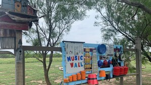 A music wall with various musical instruments and storage bins.