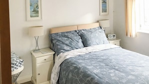 A bedroom with a bed, bedside tables, lamps, and framed pictures on the wall. - 2 bedroom accommodation in Seahouses (Seahouses)