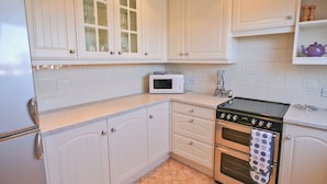 A kitchen with white cabinets, a microwave, an oven, and a refrigerator. - 2 bedroom accommodation in Seahouses (Seahouses)