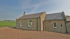 A stone building with a sloped roof and multiple windows.