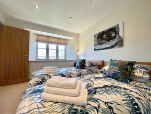 Un dormitorio con cama, ventana, puerta y un cuadro colgado en la pared.