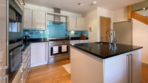 A modern kitchen with stainless steel appliances, white cabinetry, and a black countertop island.