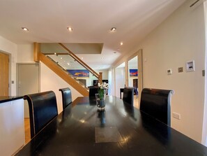 A conference room with a long table, black chairs, a vase with flowers, and a staircase in the background. - 4 bedroom accommodation in Wells (Wells)