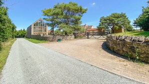 A rural road leading to a stone wall and a wooden gate.