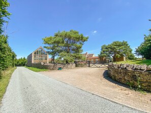 Un chemin de campagne menant à un mur de pierres et à une porte en bois.