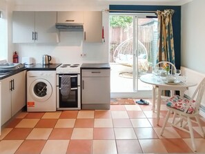 A compact kitchen with a washing machine, stove, and dining area with a table and chairs.