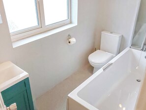 A bathroom with a toilet, a bathtub, and a window.