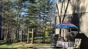 A patio area with a grill, outdoor furniture, and a striped umbrella. - 3 Dog Night (Vacation Rental) Private. 7 min to T.I.E.C (Mill Spring)