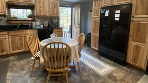 A kitchen with wooden cabinets, a black refrigerator, and a dining table with chairs. - 3 Dog Night (Vacation Rental) Private. 7 min to T.I.E.C (Mill Spring)