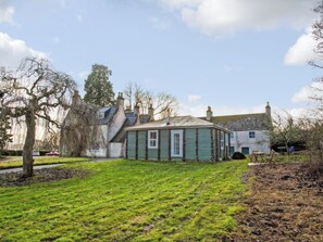 A traditional house with a green facade, a grassy yard, and a clear sky.