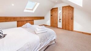 Ein Schlafzimmer mit Dachfenster, einem Holzschrank und einem ordentlich bezogenen Bett mit Handtüchern.