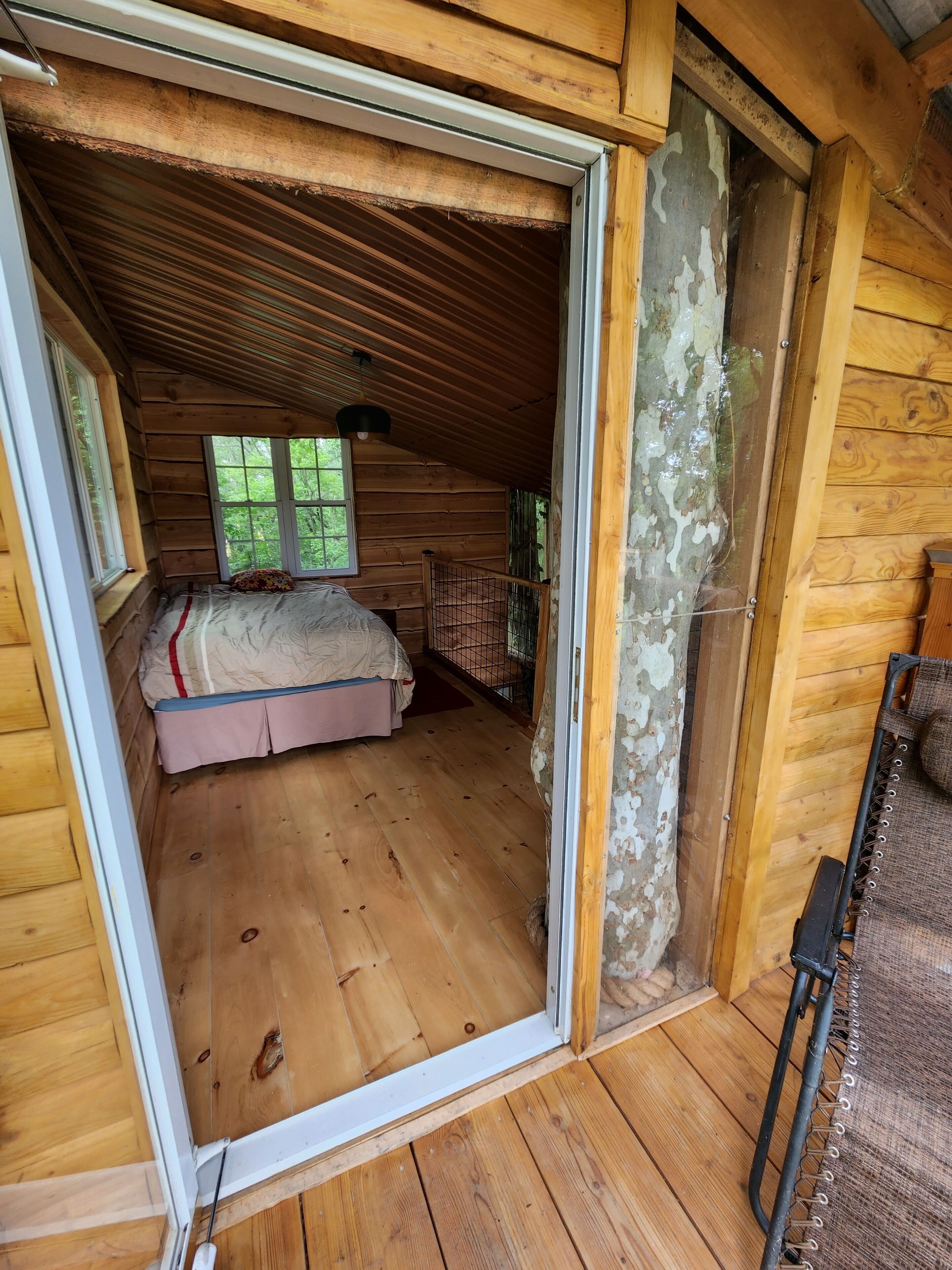 Une pièce dans un chalet en bois, avec un lit, une fenêtre et une porte.