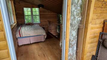 Une pièce dans un chalet en bois, avec un lit, une fenêtre et une porte.