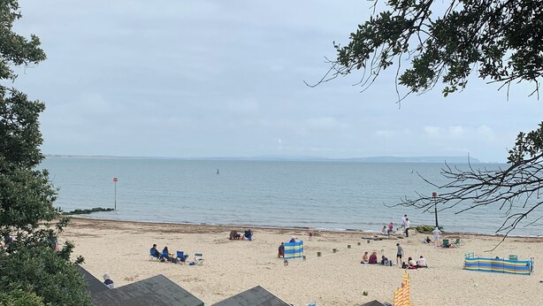 Une plage avec plusieurs cabanes de plage, un rivage sablonneux et une mer calme.