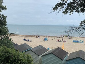 A beach with several beach huts, a sandy shore, and a calm sea.