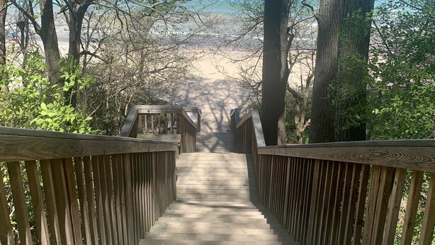 A wooden staircase leading to a beach with a clear view of the ocean.