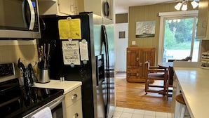 A kitchen with a black refrigerator, a stove, and a wooden cabinet.