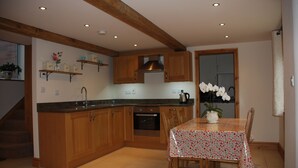 A kitchen with wooden cabinets, a dining table with a floral tablecloth, and a potted orchid.