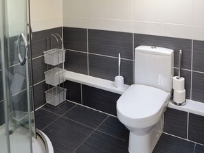 A modern bathroom with a toilet, a shower, and a sink.