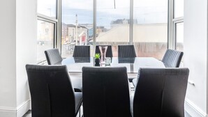 Kokoushuone, jossa on suuri ikkuna, kolme mustaa tuolia, lasipöytä ja pieni kasvi.