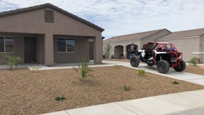 A modern two-story house with a paved driveway and a red ATV parked in front.