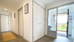 A hallway with white doors, a yellow mat, and a window with a view of the outdoors.