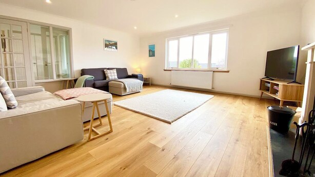 A spacious living room with a sofa, a coffee table, a TV, and a large window.