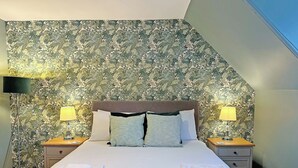 A hotel room with a large bed, two bedside tables, a flat-screen TV, and a floral wallpaper. - 2 bedroom accommodation in Lamlash, Isle of Arran (Lamlash, Isle of Arran)