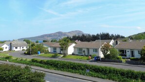 A residential area with houses, a road, and a mountain in the background. - 2 bedroom accommodation in Lamlash, Isle of Arran (Lamlash, Isle of Arran)