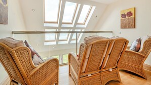 A spacious room with a high ceiling, large windows, and wicker furniture. - 3 bedroom accommodation in Port Lamont near Dunoon (Port Lamont near Dunoon)