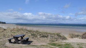 A beach with a picnic table and grassy dunes. - 2 bedroom accommodation in Nairn, Morayshire (Nairn, Morayshire)