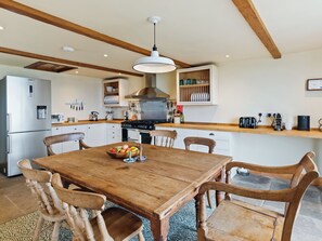 Una cocina con armarios de madera, una estufa y una mesa de comedor con sillas.