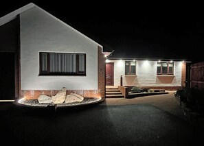 Una casa moderna con fachada blanca, sección inferior de ladrillo y entrada bien iluminada.