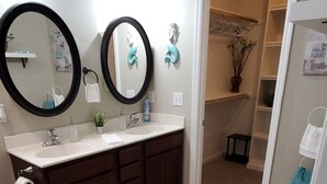 A bathroom with two sinks, dark cabinets, a white rug, and a door leading to a closet. - Horse Ranch Getaway (Richlands)